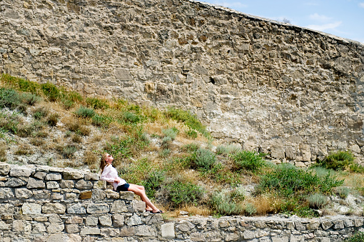 the girl lies on the stone steps in the distance, and behind her the sloping old wall. Traveler essays
