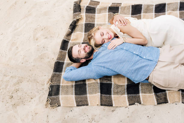 istock happy couple lying together on plaid blanket at sandy beach 1177724324