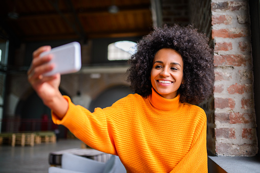Young smiling woman taking a selfie at the coffee shop