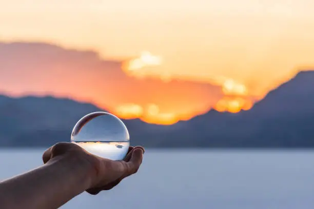 Photo of Bonneville Salt Flats colorful landscape bokeh background with hand holding crystal ball near Salt Lake City, Utah and mountain view and sunset