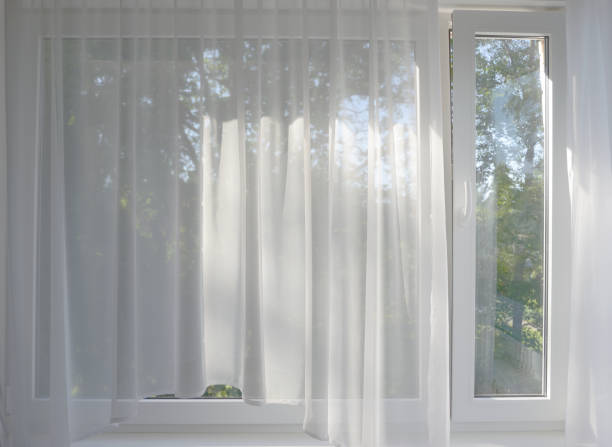 the morning garden in the window behind the transparent curtains stock photo