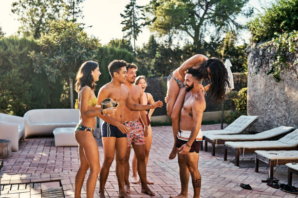 istock Friends looking at man lifting woman on poolside 1177752009