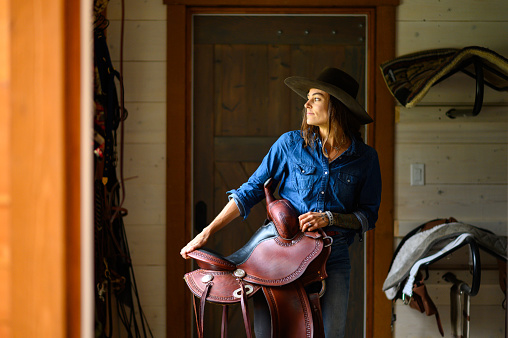 Female farmer in a tacking room. Rancher working on a Canadian ranch. Empowered woman working in agriculture.