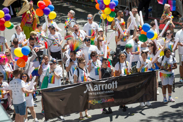 Marriott International Employees in the Seattle Gay Pride Parade Seattle Pride is in full swing with the 2018 summer Gay Pride Parade. One of the largest in the USA, Seattle gay pride showcases entrants from local and national companies including T-Mobile, Nordstrom, Google, Facebook, and other local employers.  Marriott employees carry a banner while they march. gay pride parade photos stock pictures, royalty-free photos & images