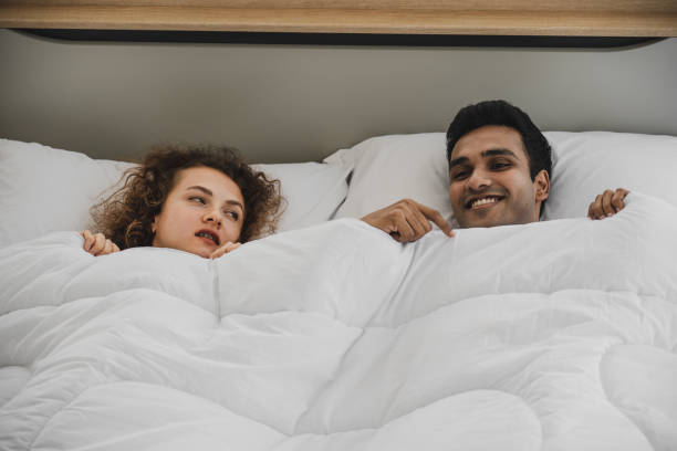istock a man and a woman lying on a bed 1177764592