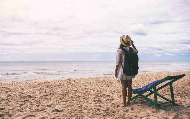 istock A female traveler with hat and backpack standing alone on the beach 1177767398