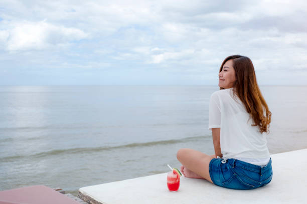istock woman drinking watermelon juice while sitting by the sea 1177767424