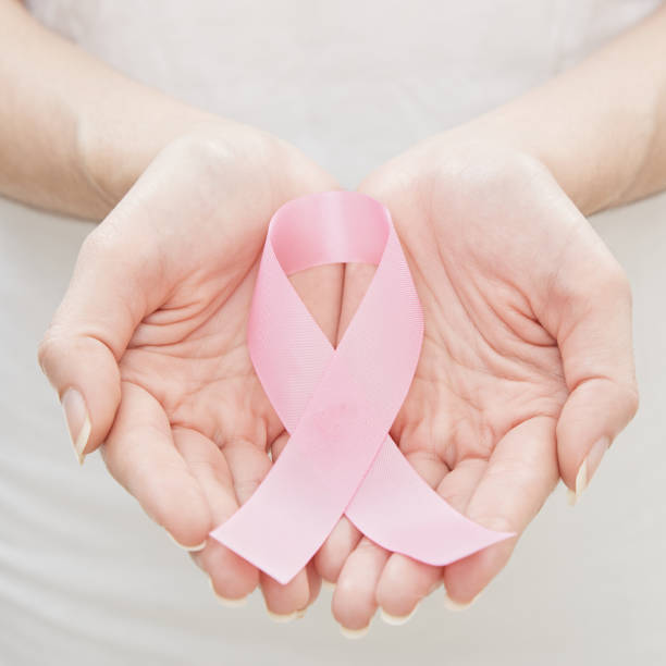 Woman wearing white top holding pink ribbon as a symbol of breast cancer in her hands. Woman wearing white top holding pink ribbon as a symbol of breast cancer in her hands. healthcare and medicine Oncological disease concept militant groups photos stock pictures, royalty-free photos & images