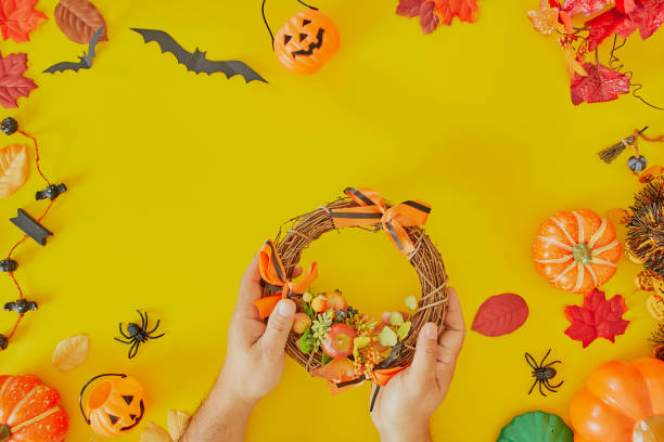 istock Hands holding cedar branches on yellow table. Details for workshop of making halloween wreath 1177771939