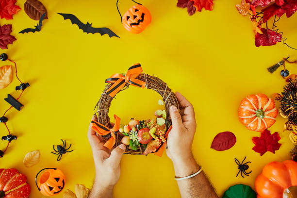 istock Hands holding cedar branches on yellow table. Details for workshop of making halloween wreath 1177771940