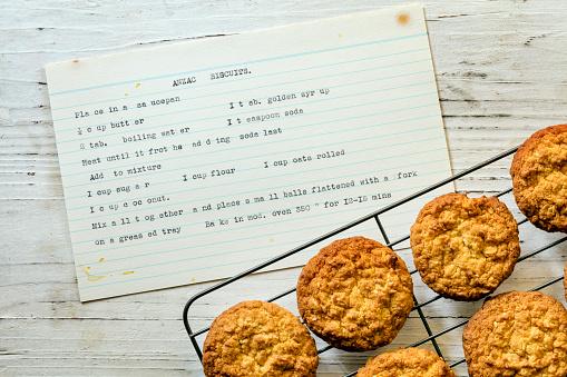 Anzac biscuits on rack with vintage typewritten recipe.  Top view on rustic timber.