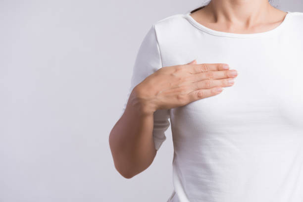 회색 배경에 유방암의 표시를 위해 그녀의 유방에 덩어리를 검사하는 여자 손. 헬스케어 개념. - breast chest the human body human skin 뉴스 사진 이미지