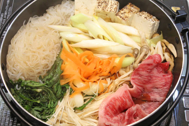 Japanese sukiyaki.Sukiyaki  is a hot pot dish made from meat, tofu, long green onion, shirataki noodles, and other vegetables, simmered in a salty-sweet sauce. Japanese sukiyaki.Sukiyaki  is a hot pot dish made from meat, tofu, long green onion, shirataki noodles, and other vegetables, simmered in a salty-sweet sauce. crown daisy stock pictures, royalty-free photos & images