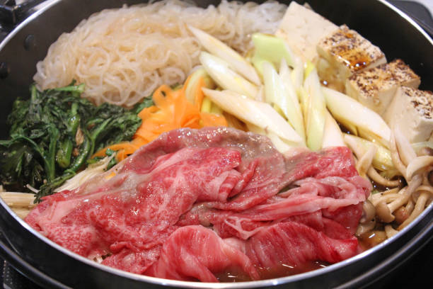 Japanese sukiyaki.Sukiyaki  is a hot pot dish made from meat, tofu, long green onion, shirataki noodles, and other vegetables, simmered in a salty-sweet sauce. Japanese sukiyaki.Sukiyaki  is a hot pot dish made from meat, tofu, long green onion, shirataki noodles, and other vegetables, simmered in a salty-sweet sauce. crown daisy stock pictures, royalty-free photos & images