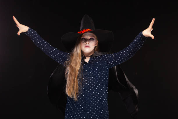 istock Halloween. Witch with a spider on his hat on black background Casts a spell with his hands. Beautiful young surprised woman in witches hat and costume holding. Wide Halloween party art design. Copy-paste. Witch craft concept 1177790908