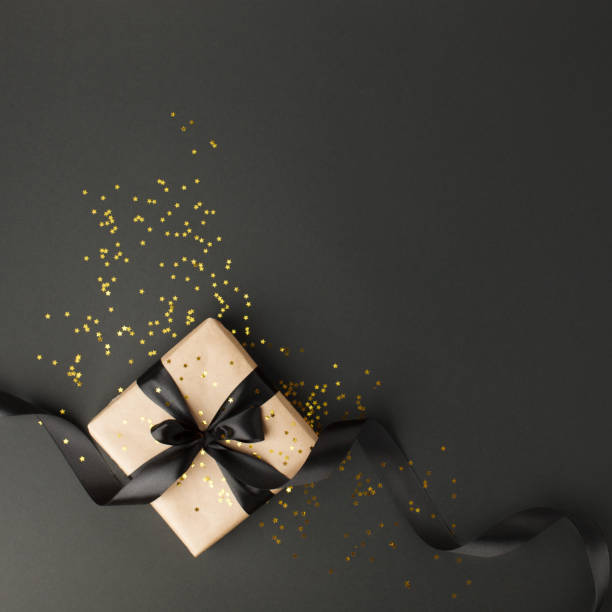 istock Gift or present box and gold stars confetti on black table top view. Flat lay composition for birthday, mother day, black friday sale, xmas, christmas, new yaer or wedding. 1177801007