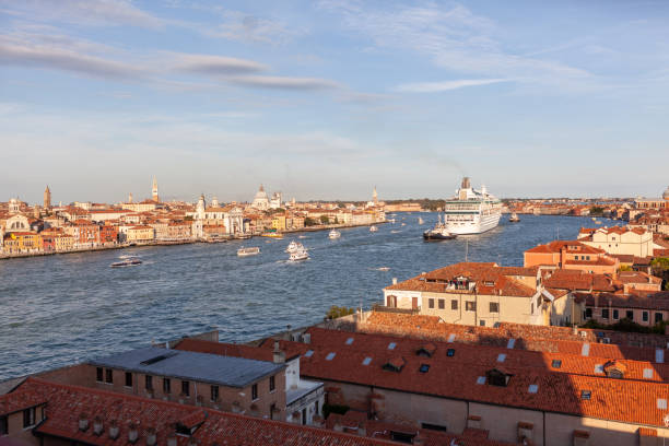 A huge cruise ship in Canale della Giudecca in Venice lagoon moving toward St. Mark basin (bacino di San Marco). Seen from Skyline Rooftop Bar on Hilton hotel Molino Stucky  in Giudecca Island  in the late evening.