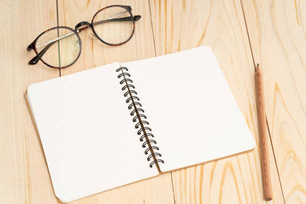 istock Blank notebook and reading glasses on wood table 1177808758