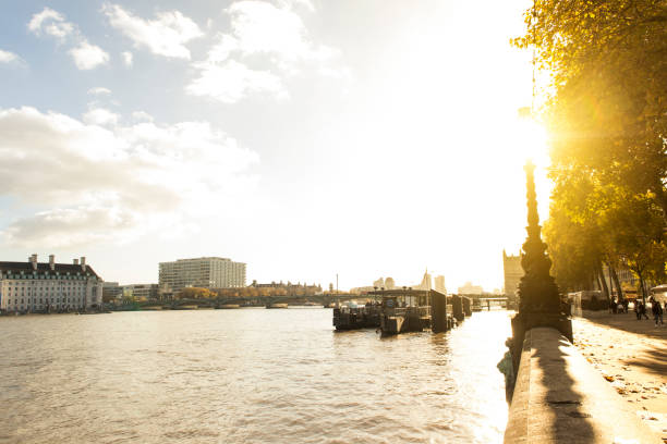 Somerset House on Thames River in City of Westminster, London. Commercial signs are visible on the barges.