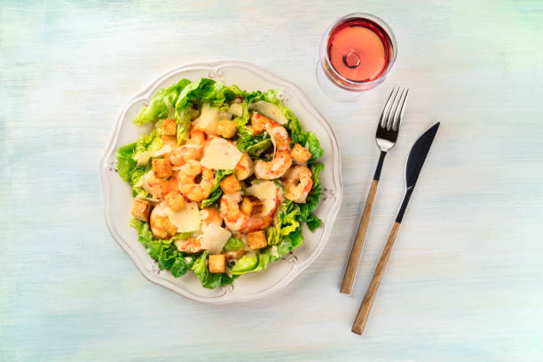 shrimp caesar salad with parmesan cheese, croutons and lettuce, with a glass of rose wine - salad food and drink food lettuce imagens e fotografias de stock