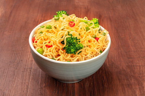 Soba noodles with broccoli and peppers on a dark rustic wooden background
