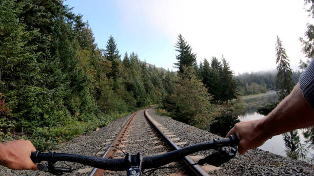l'homme monte des vélos le long des voies ferrées le matin - personal perspective mountain biking mountain bike cycling photos et images de collection