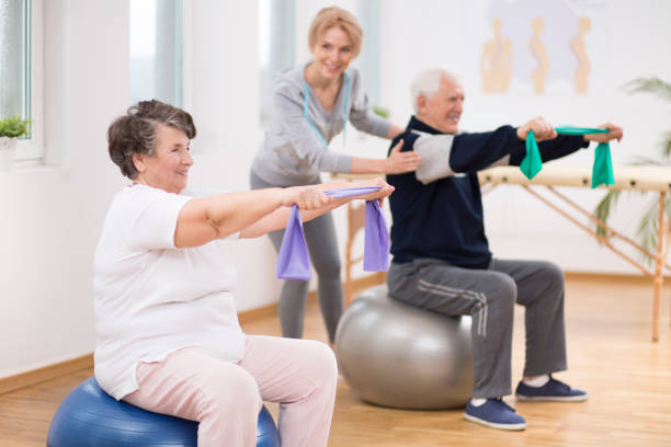 anziano uomo e donna che si allena sulle palle ginnastica durante la sessione di fisioterapia in ospedale - doctor old male family foto e immagini stock