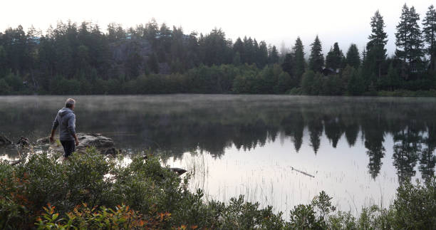 istock Man walks along lakeside rocks in the morning 1177820010