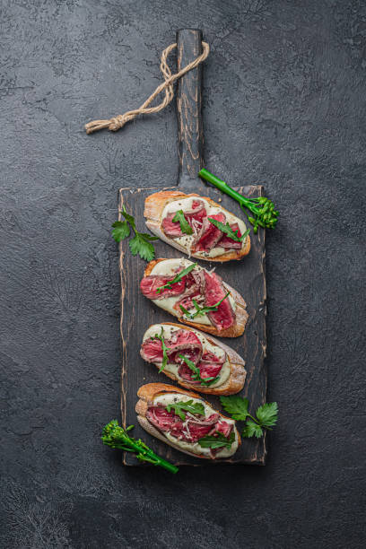 bruschettas con carne de res sobre tabla de madera, planas - dessert buffet italian culture food fotografías e imágenes de stock