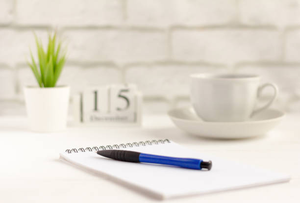 a clean notebook with a pen and a coffee Cup on the table by the window
