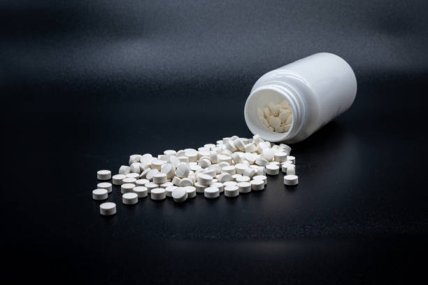 istock a pile of white pills in front of a half empty bottle 1177822792