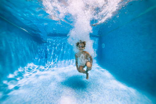 Underwater portrait of a little boy after cannonballing to swimming pool.\nShot with Nikon D850