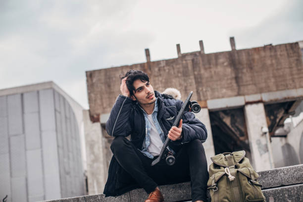 istock Young man with skateboard sitting on stairs 1177824180