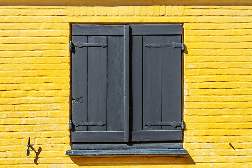 Wooden window with shutters on a yellow, brick facade. Architecture. Details