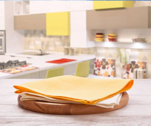 Photo of Empty pizza board with tablecloth on the table and kitchen interior background