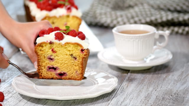 A Slice of berry cake with raspberries and lemon glaze.