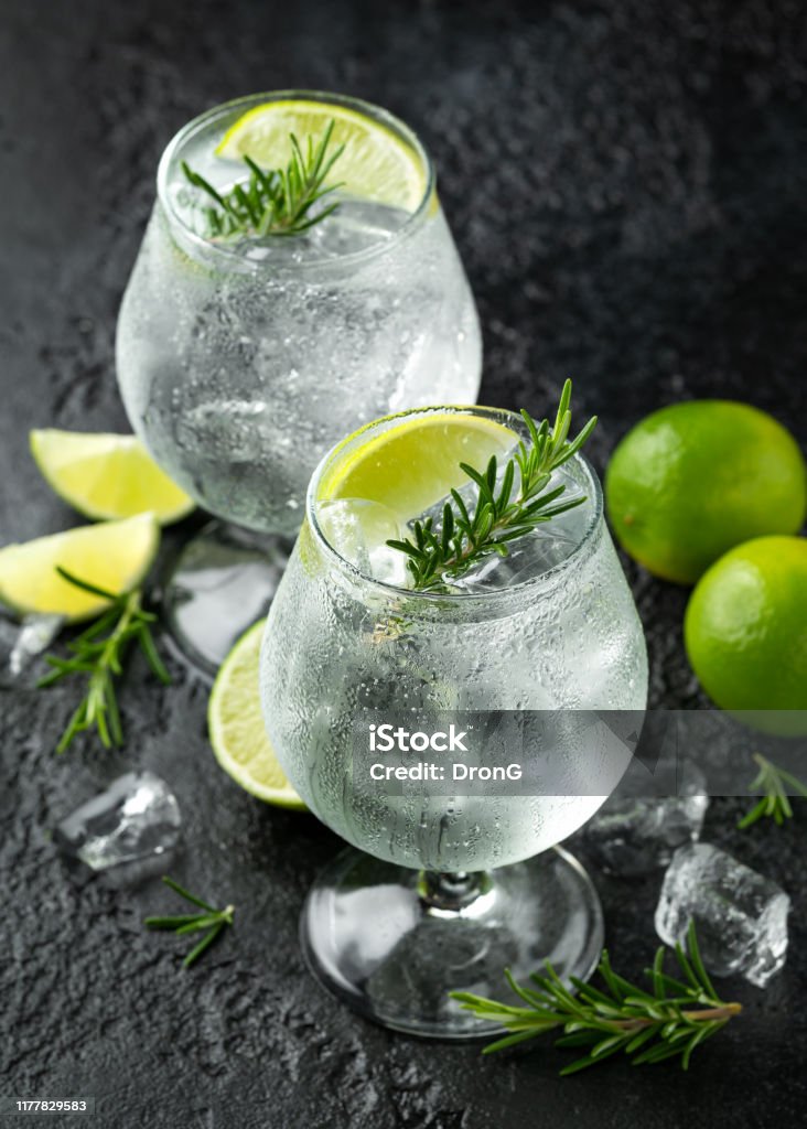 Gin and Tonic Alcohol drink with Lime, Rosemary and ice on rustic black table Gin and Tonic Alcohol drink with Lime, Rosemary and ice on rustic black table. Gin Tonic Stock Photo