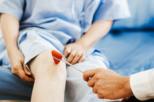 Doctor checking reflexes of a patient on the knee with reflex hammer