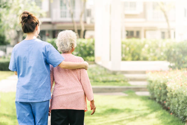 高齢女性と屋外で歩く介護者 - シルバー ストックフォトと画像