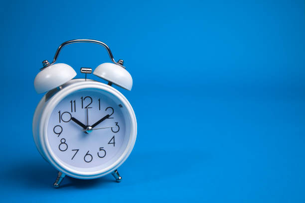 istock A white alarm clock on a blue background. a top view. 1177834577