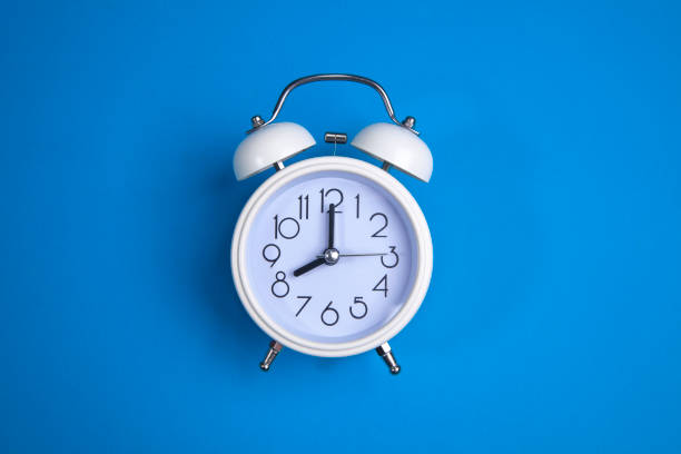 istock A white alarm clock on a blue background. a top view. 1177834680