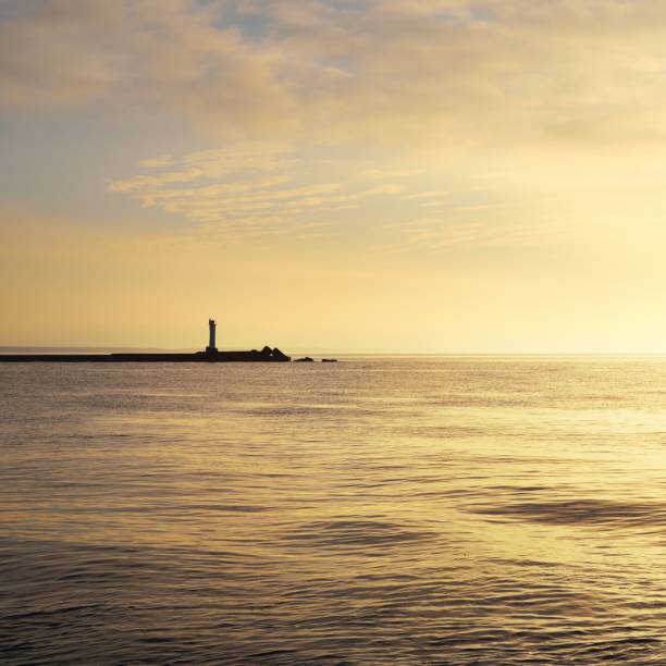 istock Horizontal image of a distant lighthouse silhouette on a stone pier on daugava river in Riga at sunset 1177837451
