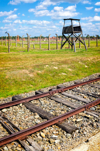 Auschwitz - Birkenau, Poland - August 11 2019:The railway platform where prisoners were brought during World War II. The barbed wire electrical fence with the guard's watch tower in background, Auschwitz - Birkenau, concentration camp, Poland