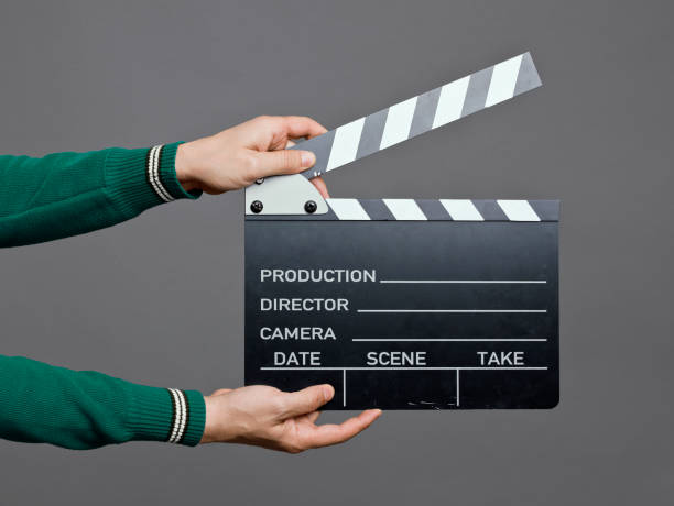 Man holding a movie clapperboard, studio shot Man holding a movie clapperboard, studio shot clapboard stock pictures, royalty-free photos & images