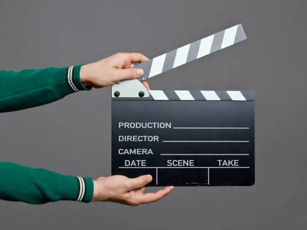 Man holding a movie clapperboard, studio shot