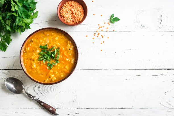 Red Lentil Soup on white wooden background, top view, copy space. Traditional turkish or arabic lentil and vegetable spicy soup, healthy vegan lunch.