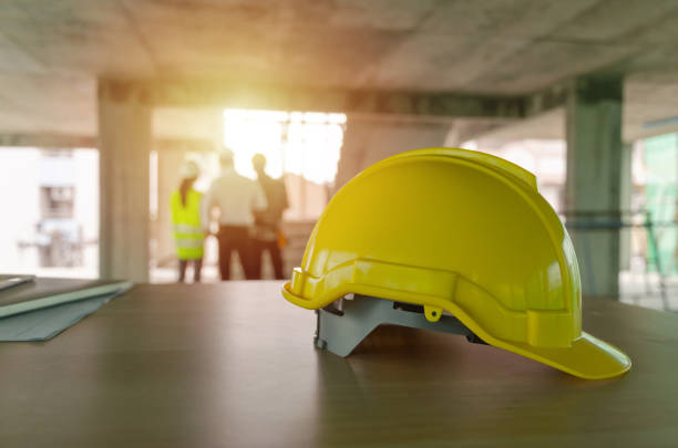 istock yellow safety helmet on workplace desk with construction worker team engineer or inspector checking new project contract at construction site background, engineering, construction, contractor concept 1177841305