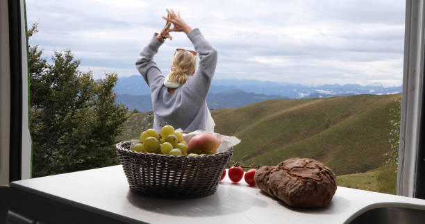 istock View past fruit to woman stretches outside motorhome 1177841480