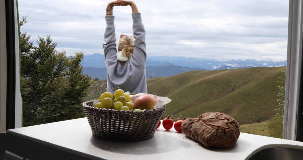 istock View past fruit to woman stretches outside motorhome 1177841485