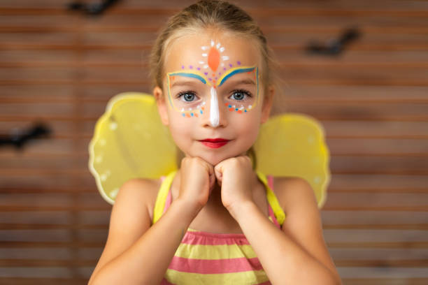 retrato de cintura arriba de preescolar lindo con pintura de la cara diy usando una mariposa halloween o traje de carnaval. - face paint human face mask carnival fotografías e imágenes de stock